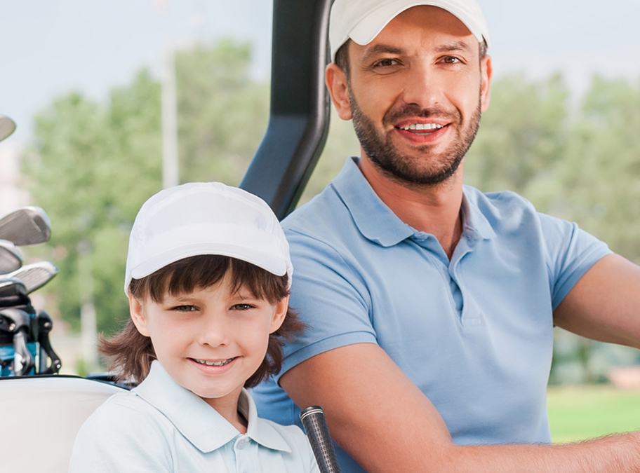 Father and son riding in a golf cart.