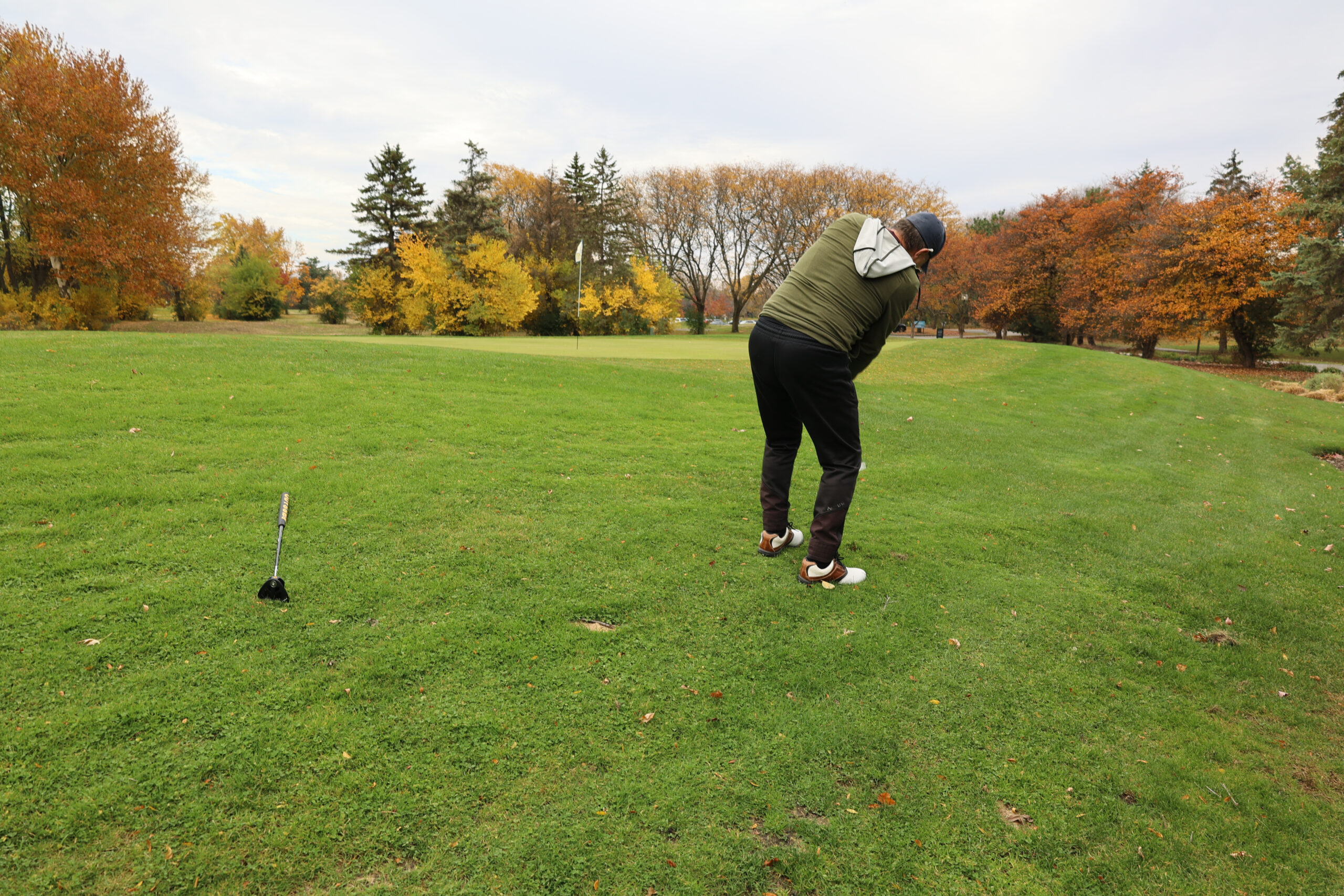 Golfer attempts a chip shot on the East Course during the fall with leaves changing