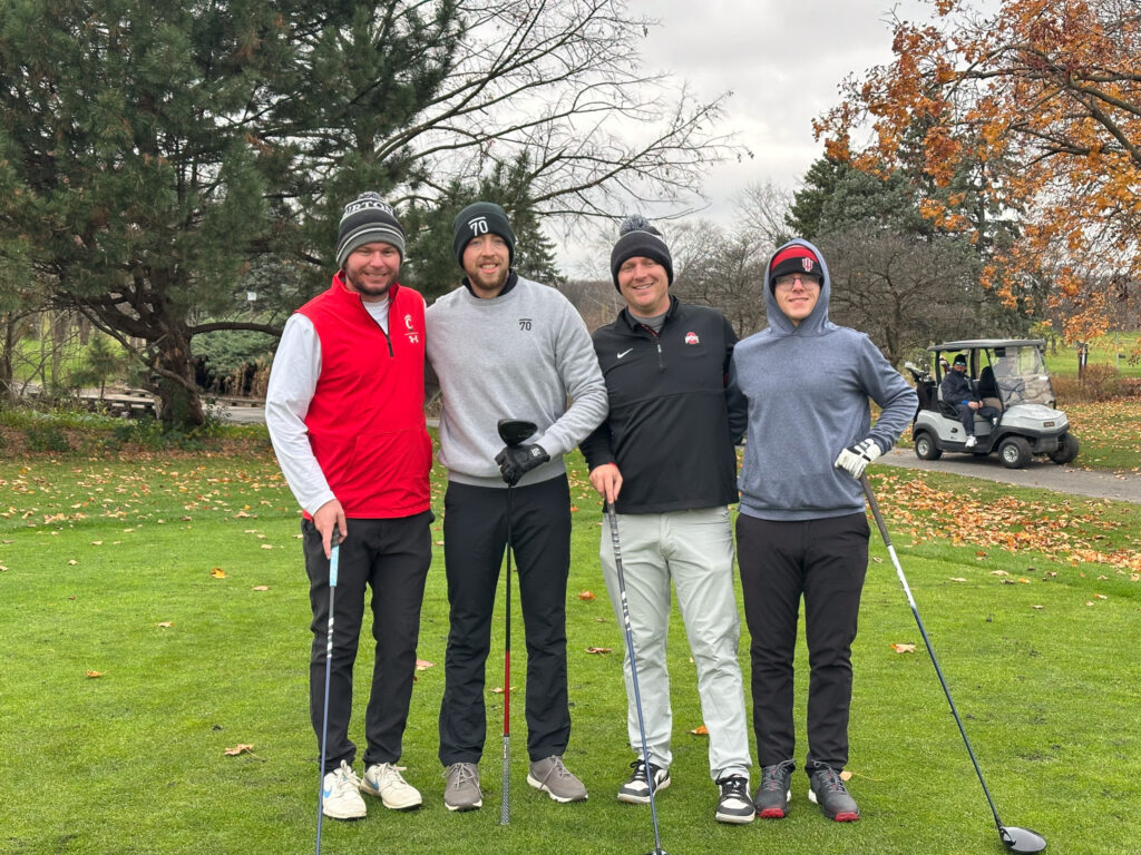 Four golfers posing for the camera while wearing winter hats. 